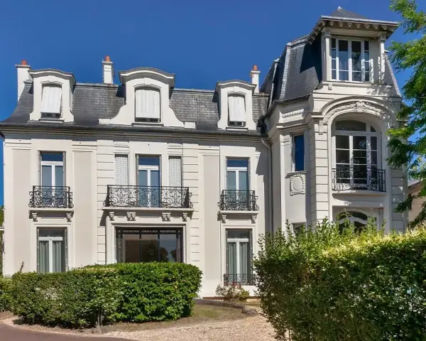 Belle demeure avec balcons en fer forgé, idéale pour une vente à réméré. Le soleil brille sur cette propriété.