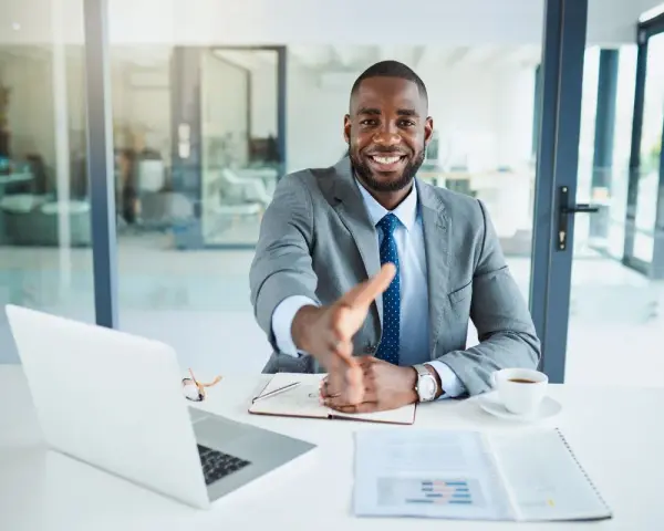 Homme d'affaires souriant, main tendue. Il est assis à son bureau, prêt à conclure un accord, rappelant la jurisprudence sur l'offre d'achat acceptée et la rétractation du vendeur.