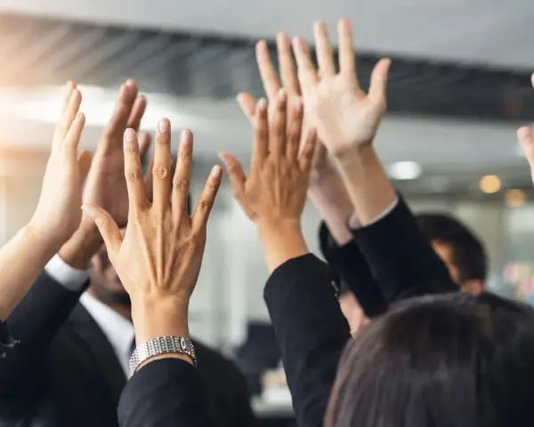 Des mains levées en signe de victoire, célébrant un succès collectif. L'équipe est unie, prête pour le quitus au syndic.