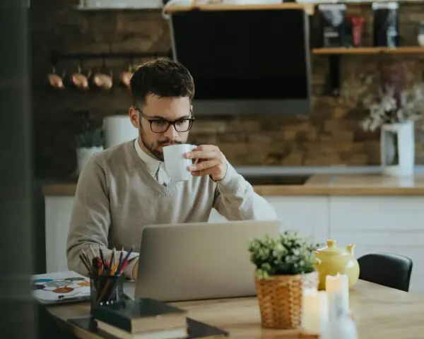 Homme buvant un café devant son ordinateur, pensant à son indemnité transactionnelle CSG CRDS.