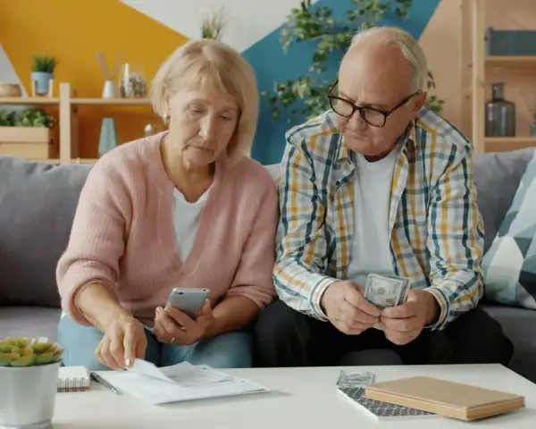 Couple âgé examinant des documents et de l'argent, peut-être pour une déclaration fiscale ou un article 83 CGI.