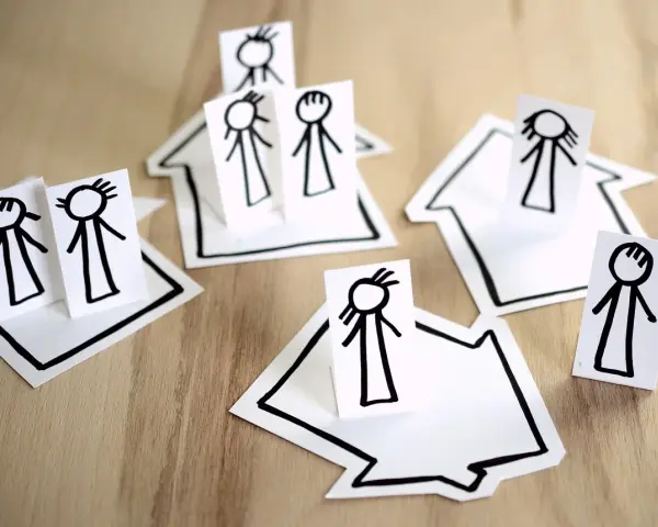Petites maisons en papier avec des bonshommes dessinés, symbolisant une famille face à un délai de prévenance et une clause de mobilité.