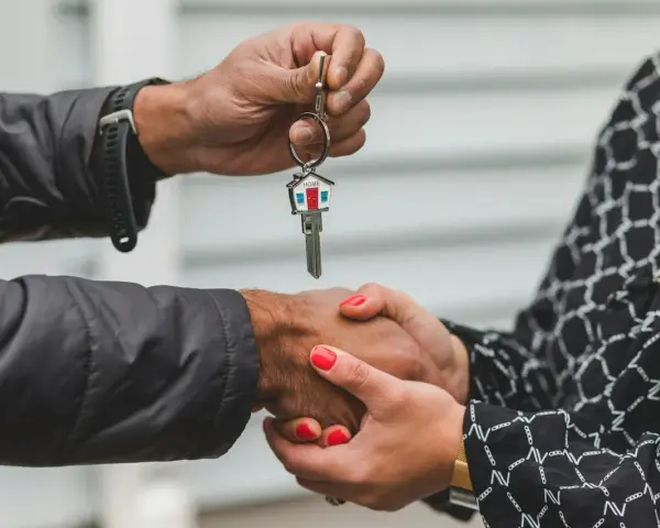 Une main tend une clé avec un porte-clés en forme de maison. Les deux mains se serrent, symbolisant la fin d'une obligation de relogement par la mairie.