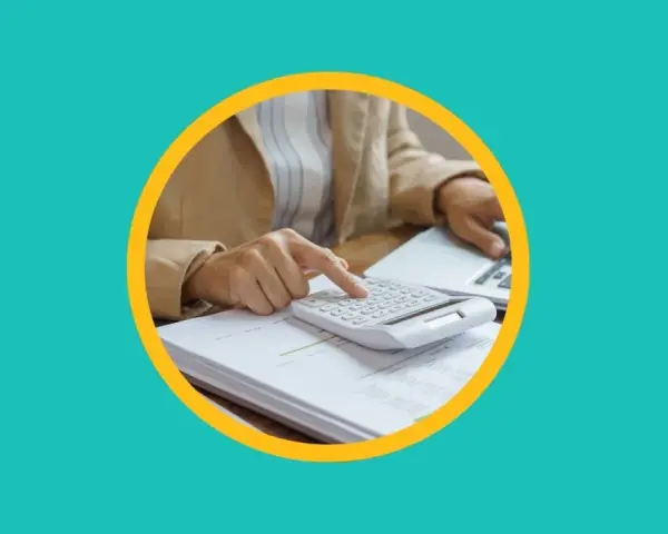 Une personne utilise une calculatrice sur des documents pour apprendre comment payer moins d'impôts.