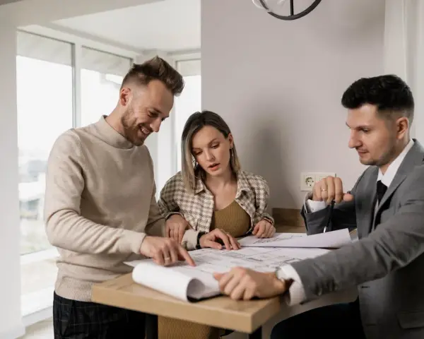 Un couple examine des plans avec un agent immobilier, illustrant l'obligation de l'agent immobilier envers l'acheteur.