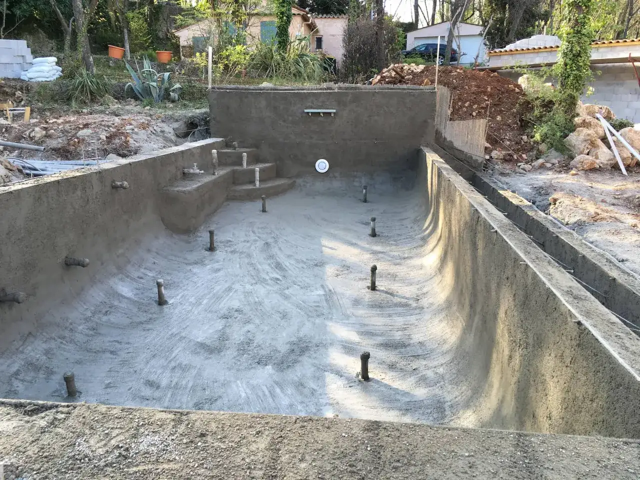 Construction d'une piscine en béton brut, avec escalier intégré. Un chantier qui bénéficie de la garantie décennale piscine pour une tranquillité assurée.