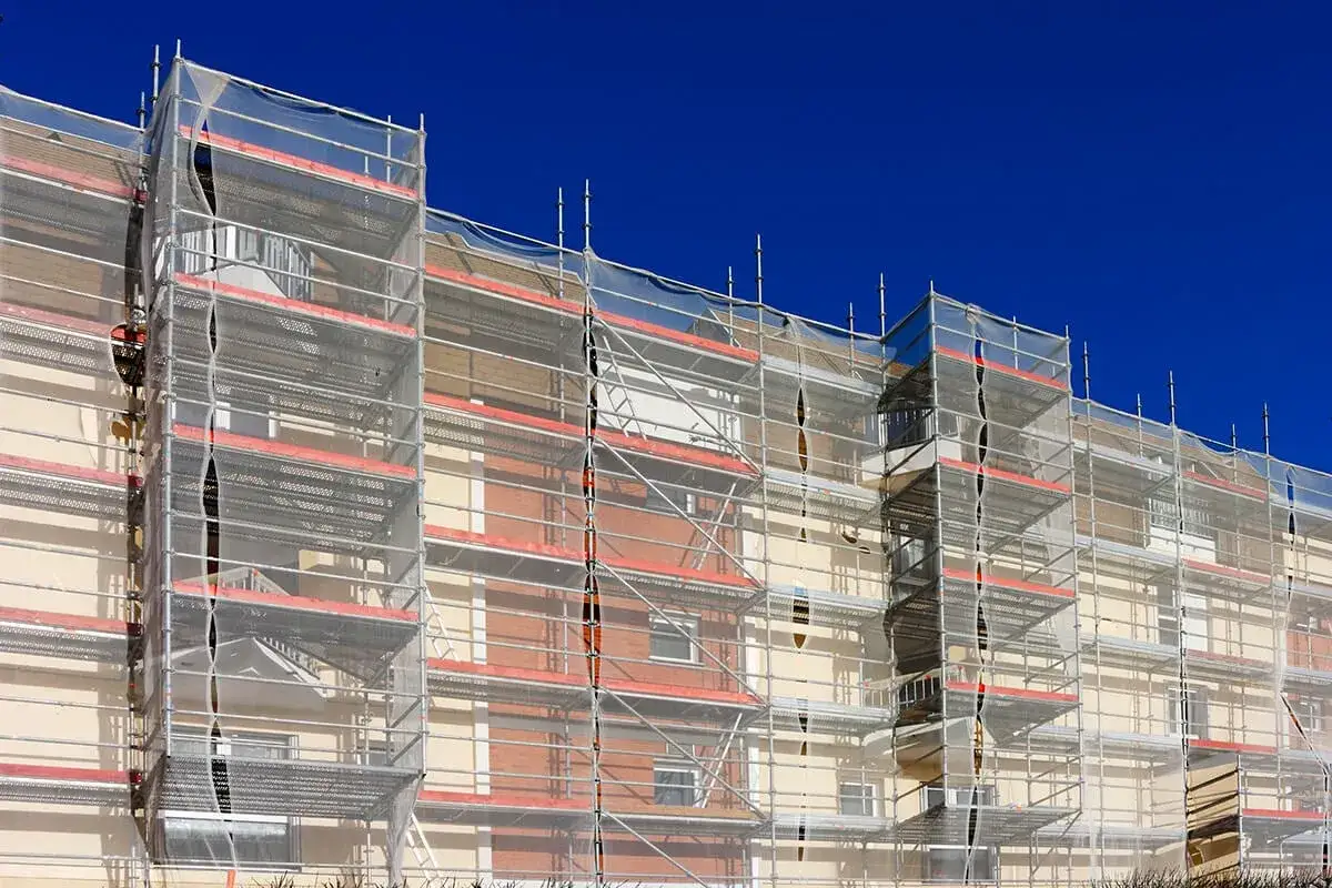 Immeuble en rénovation, entièrement recouvert d'échafaudages et de bâches. Ce chantier s'inscrit dans un plan pluriannuel de travaux pour sa modernisation.