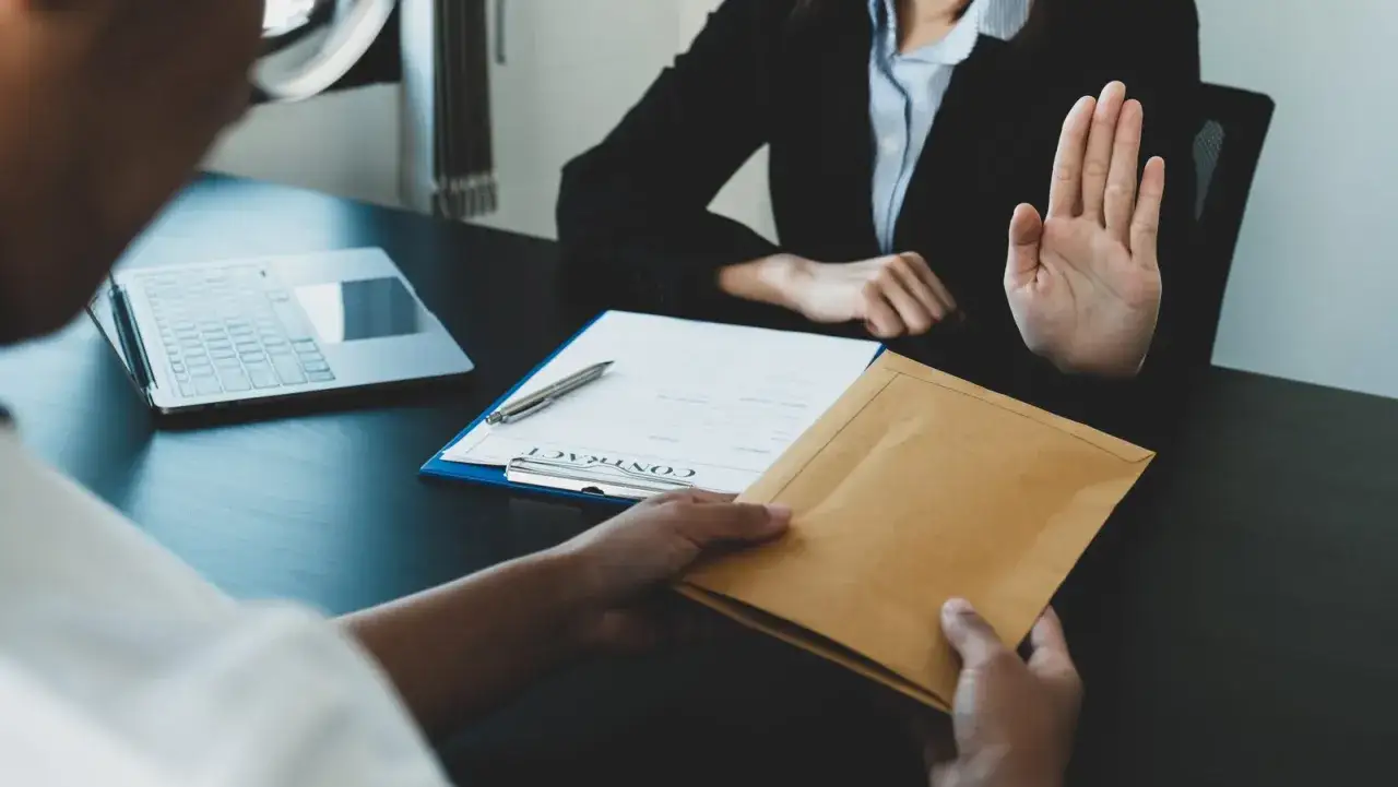 Refus d'inspection, tentative de corruption pour éviter un licenciement. Un salarié protégé tente de soudoyer, mais la main levée indique un refus ferme.