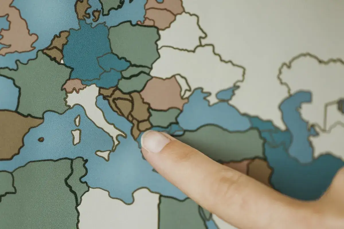 Un doigt pointe l'Italie sur une carte. Une invitation à explorer les avantages de s'expatrier en Italie et sa fiscalité.