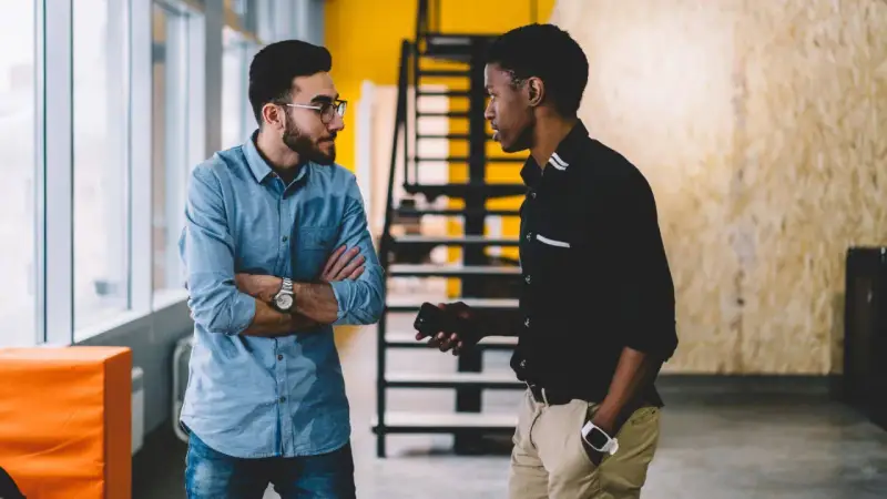 Deux hommes discutent dans un bureau. L'un semble recevoir une mauvaise nouvelle, peut-être une mise à pied sans avertissement.